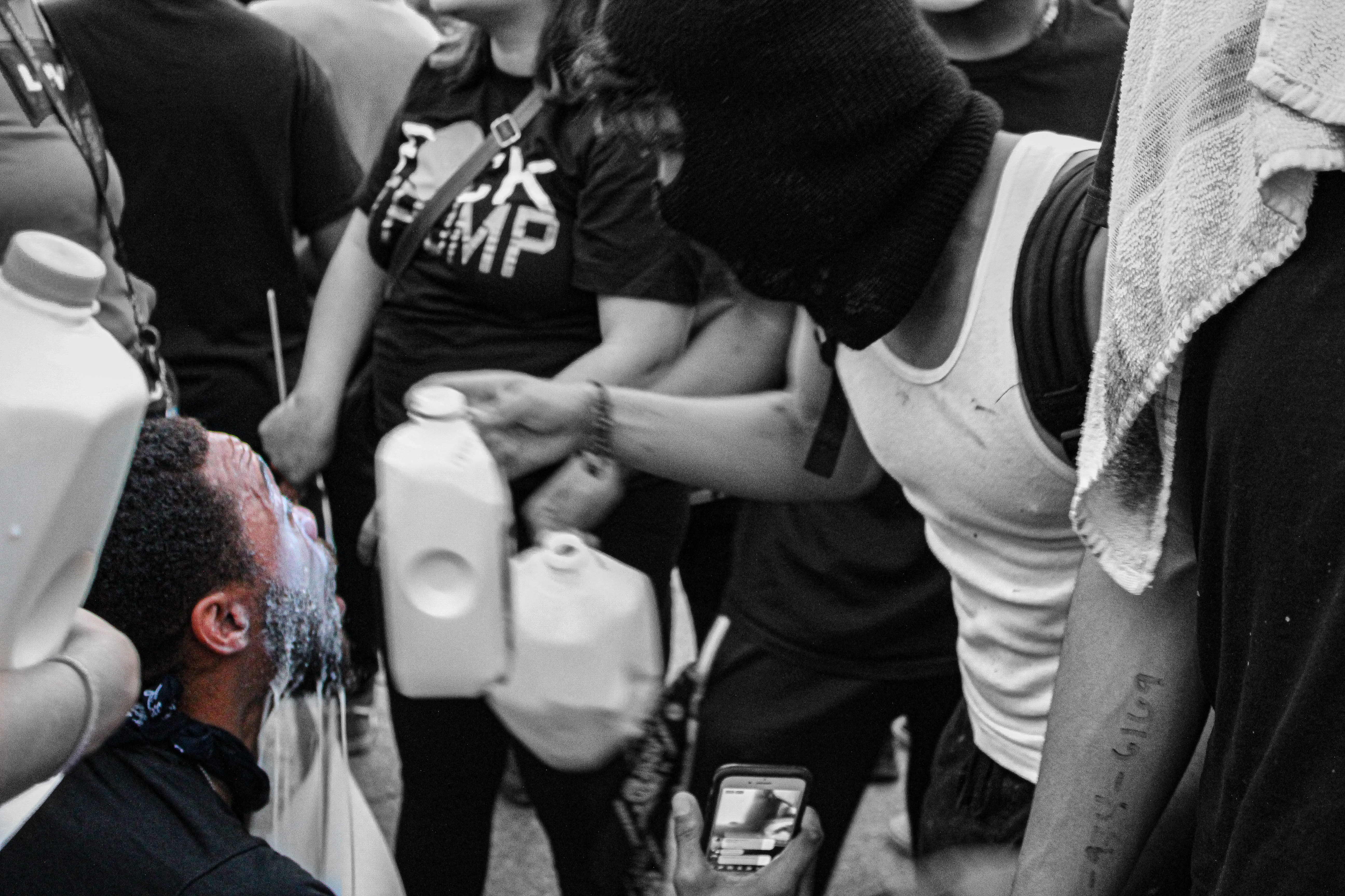 A crowd of protesters pouring milk on a person's eyes