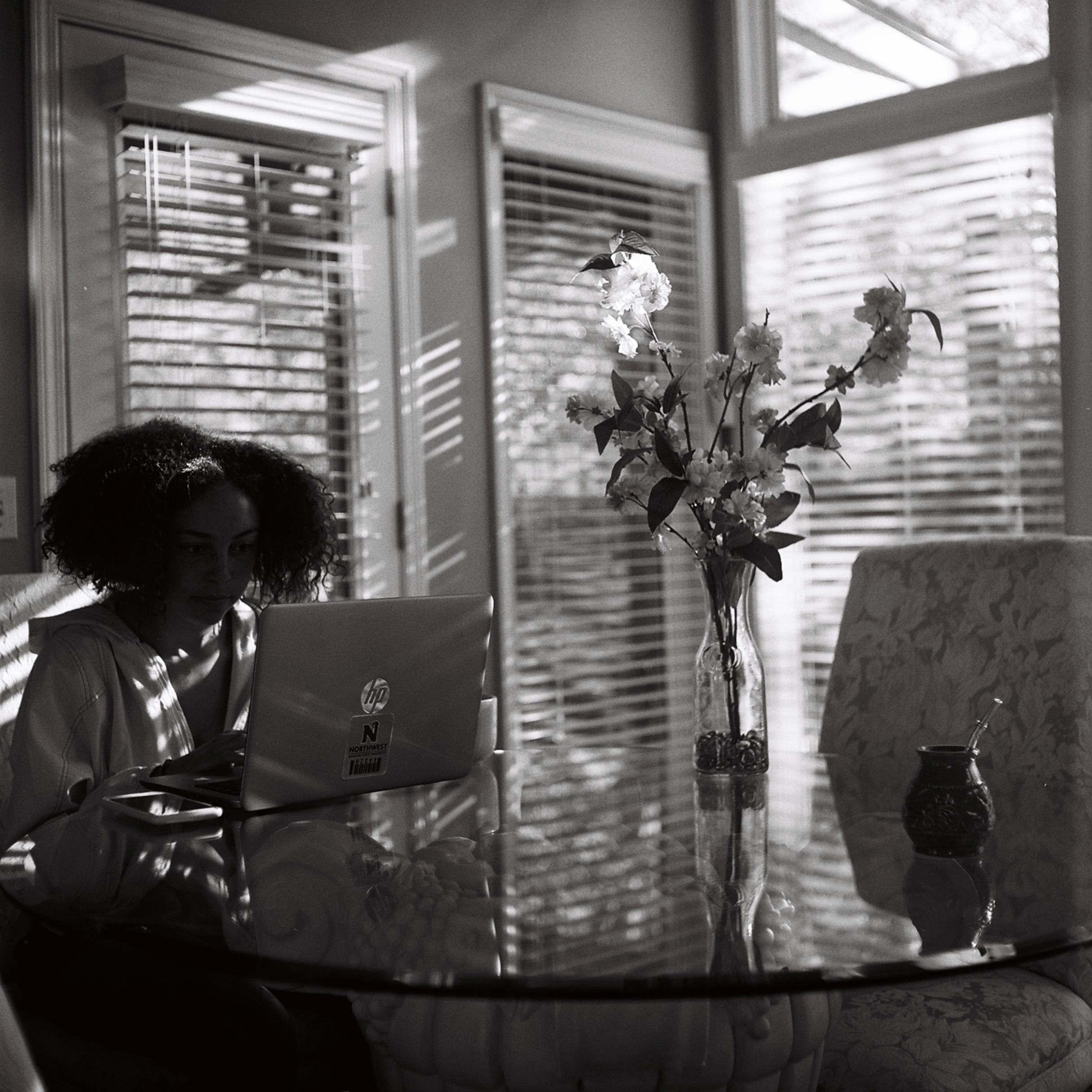 A person sitting at a table with a vase of flowers