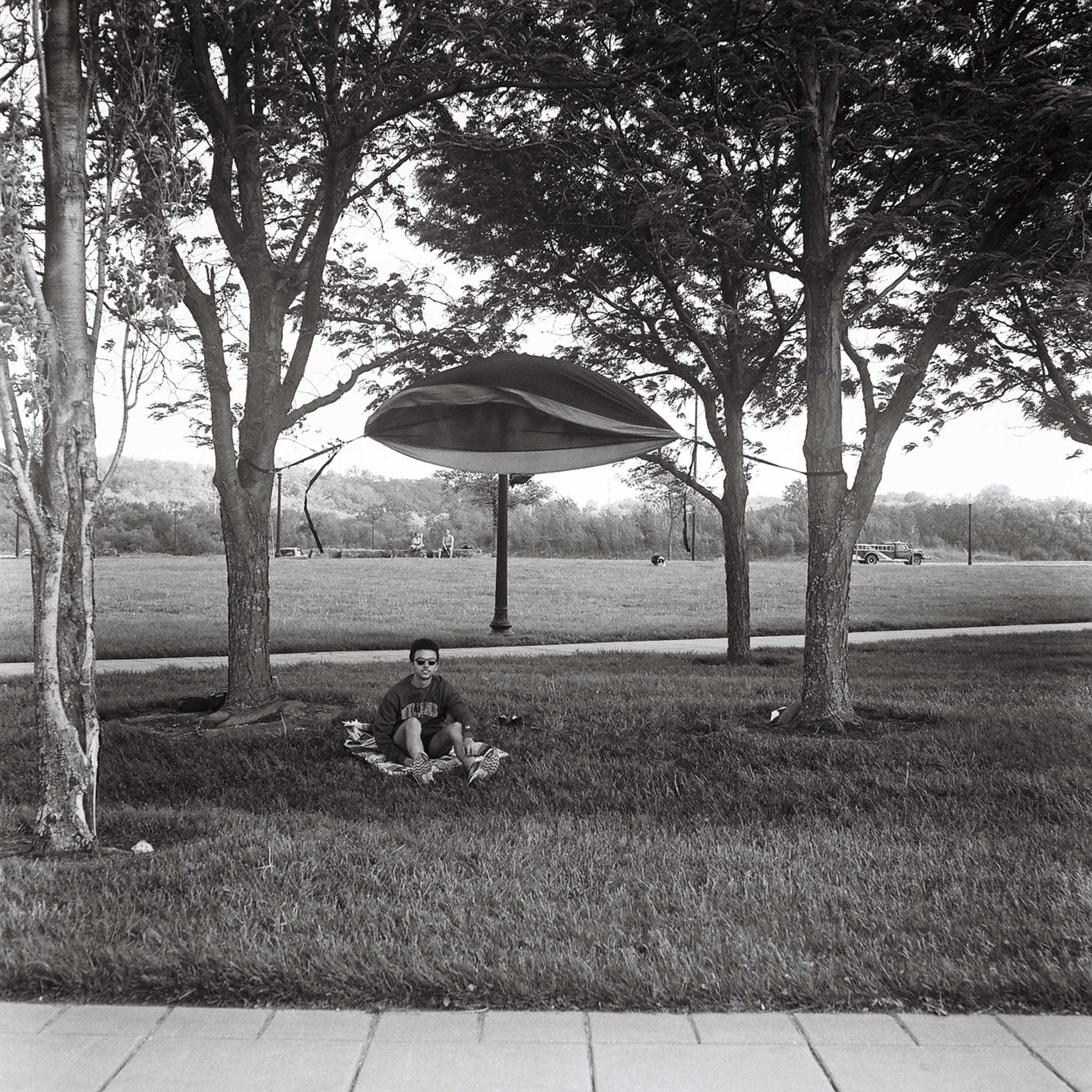 A person sitting underneath a hammock blowing in the wind